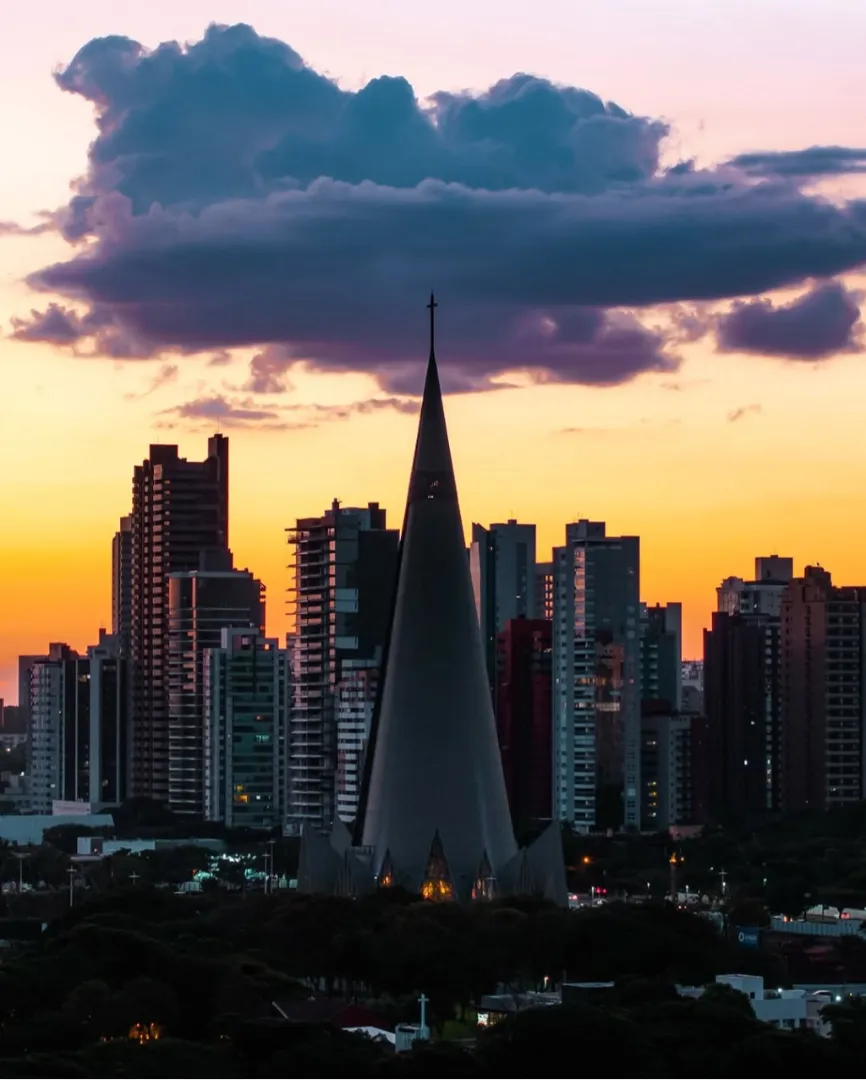 A Catedral de Maringá brilha sob a luz dourada do pôr do sol, criando um lindo espetáculo de cores e formas.